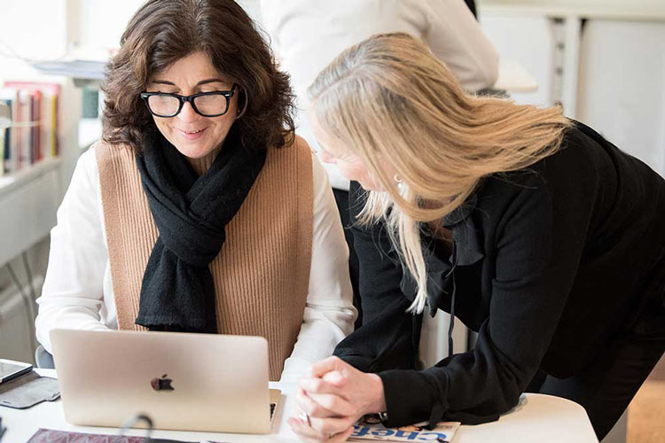 Helena Korduner från Amazing Leaders samtalar med en kollega vid en dator om framtidens ledarskap och AI.